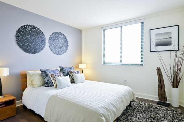 Spacious bedroom with modern furnishings at The Fillmore Center Apartments featuring stylish decor and ample lighting