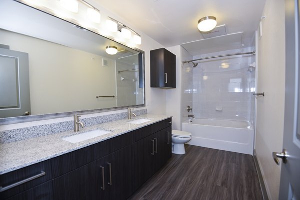 Modern bathroom with sleek fixtures and large mirror at Encore Montrose Apartments, offering luxurious living spaces