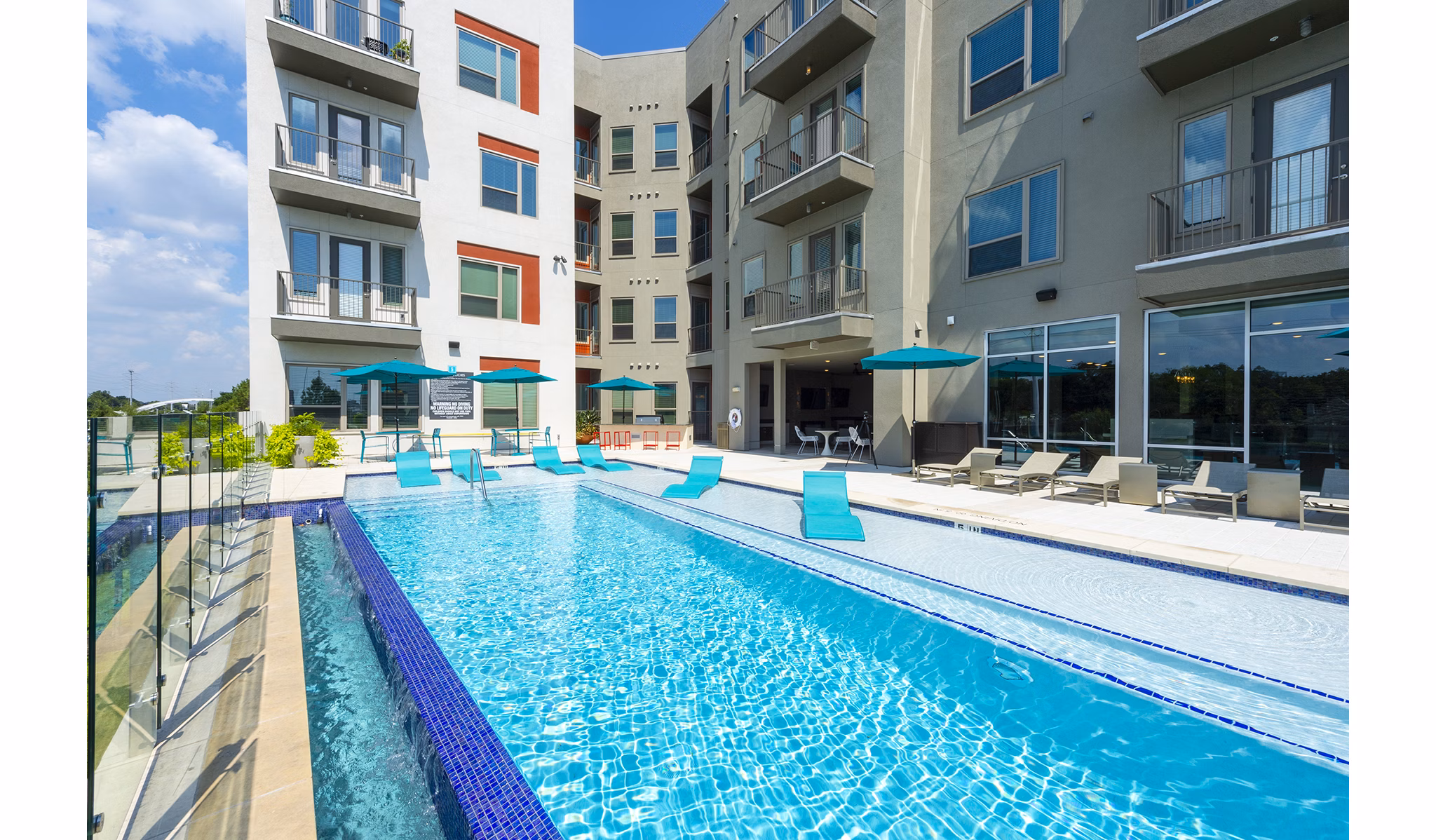Imagery of a gleaming pool bathed in sunlight, surrounded by lush greenery at the luxury Encore Montrose Apartments