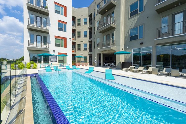 Imagery of a gleaming pool bathed in sunlight, surrounded by lush greenery at the luxury Encore Montrose Apartments