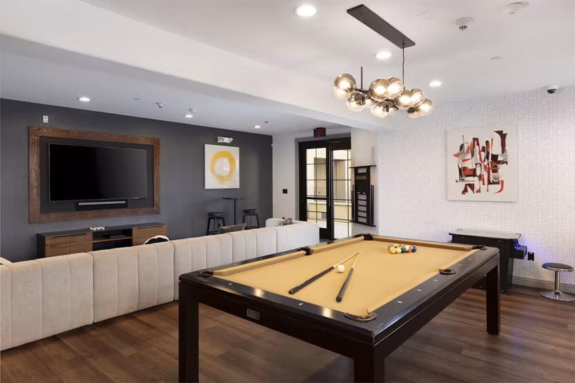 Modern game room with a pool table and wall-mounted TV in luxury apartments