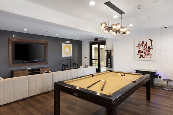 Modern game room with a pool table and wall-mounted TV in luxury apartments