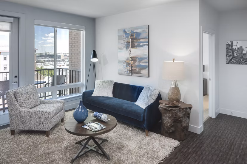 Cozy living room with modern furnishings and natural light at Alexan LoHi Apartments