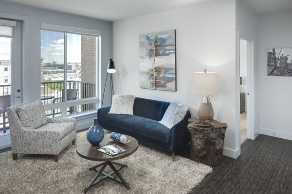 Cozy living room with modern furnishings and natural light at Alexan LoHi Apartments