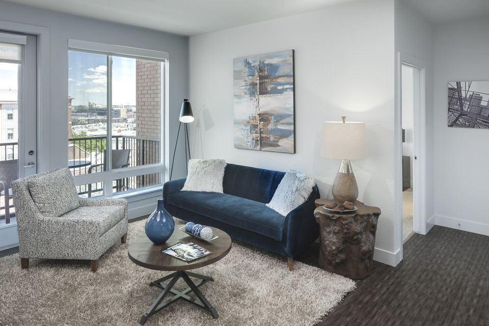 Cozy living room with modern furnishings and natural light at Alexan LoHi Apartments