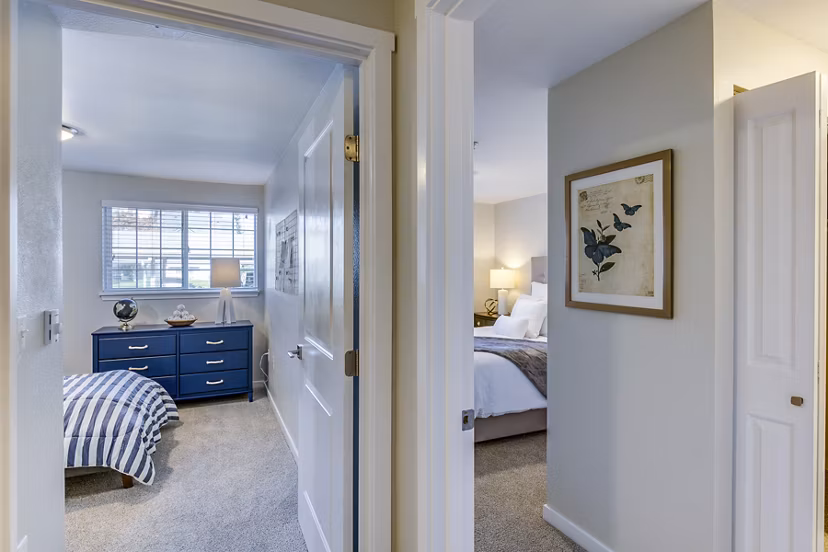 Modern hallway leading to a cozy bedroom at Callen Apartments with stylish lighting and neutral tones