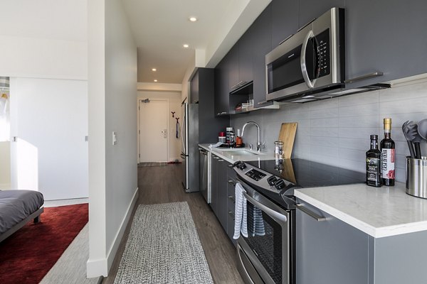Modern kitchen featuring stainless steel appliances and granite countertops in Hyde Square Apartments