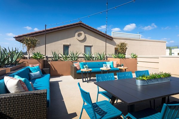 Patio balcony with cozy seating and lush greenery at Avila Apartments