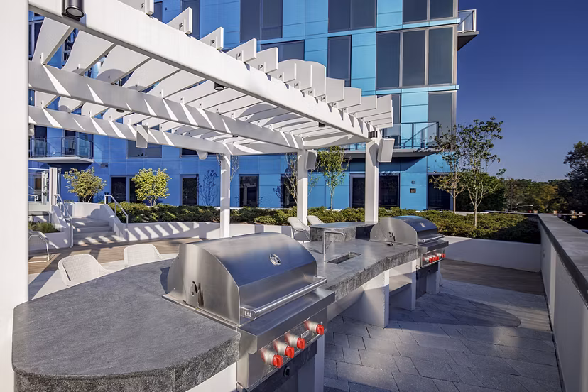 Grill area with seating and greenery at Exo Apartments, luxury living in a community offering modern outdoor amenities