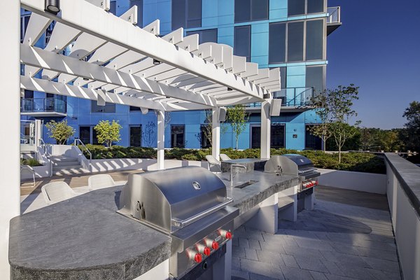 Grill area with seating and greenery at Exo Apartments, luxury living in a community offering modern outdoor amenities