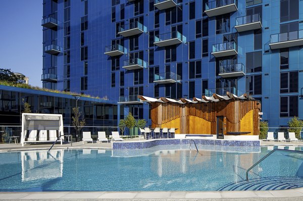 Contemporary outdoor pool at Exo Apartments featuring lounge chairs and scenic views