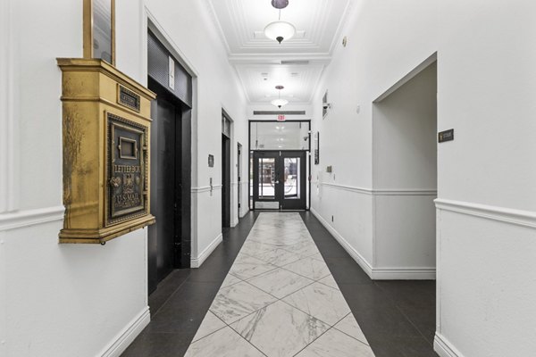 Hallway with vintage lighting and classic molding in Historic Electric Building Apartments, showcasing elegant architectural details