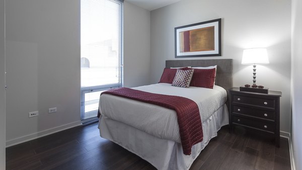 Bedroom featuring plush bedding and modern decor at Luxe on Chicago Apartments