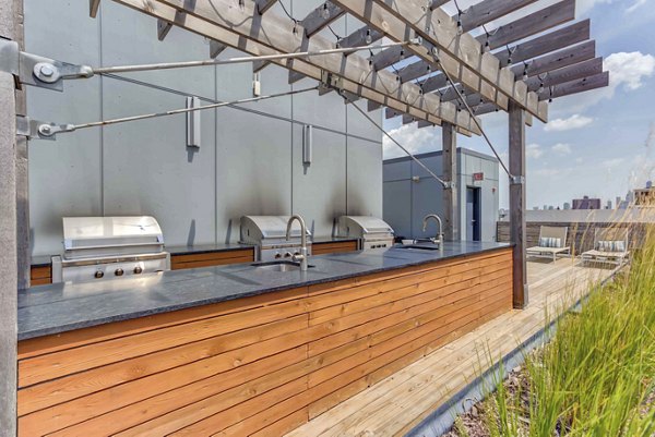 Modern outdoor grill area at Luxe on Chicago Apartments with stainless steel appliances and seating for community gatherings