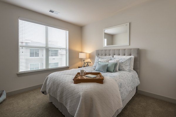 Bedroom with modern decor and plush bedding at The Franklin at Crossroads Apartments, luxury living by Greystar