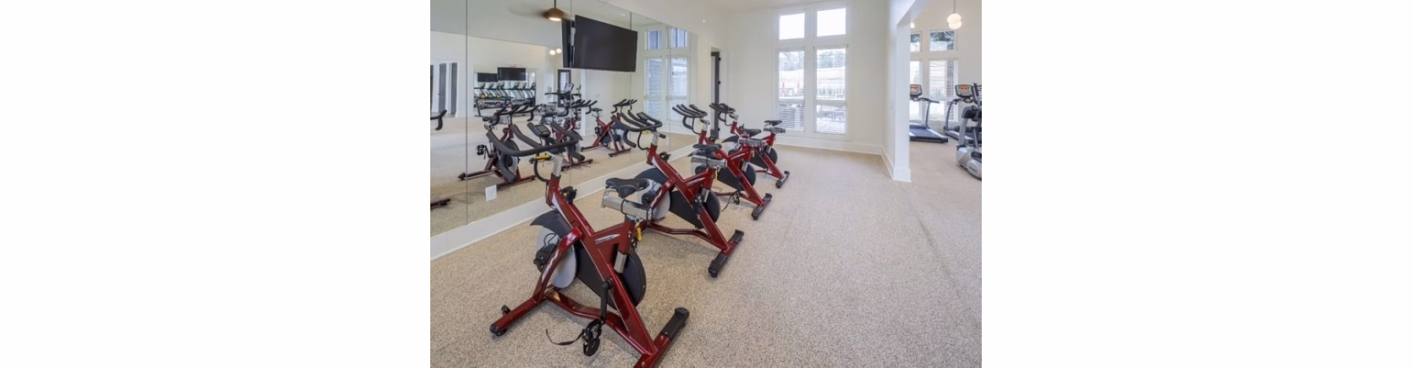 Spin studio with modern bikes and mirrors at Grand Oaks at Crane Creek Apartments, ideal for fitness enthusiasts