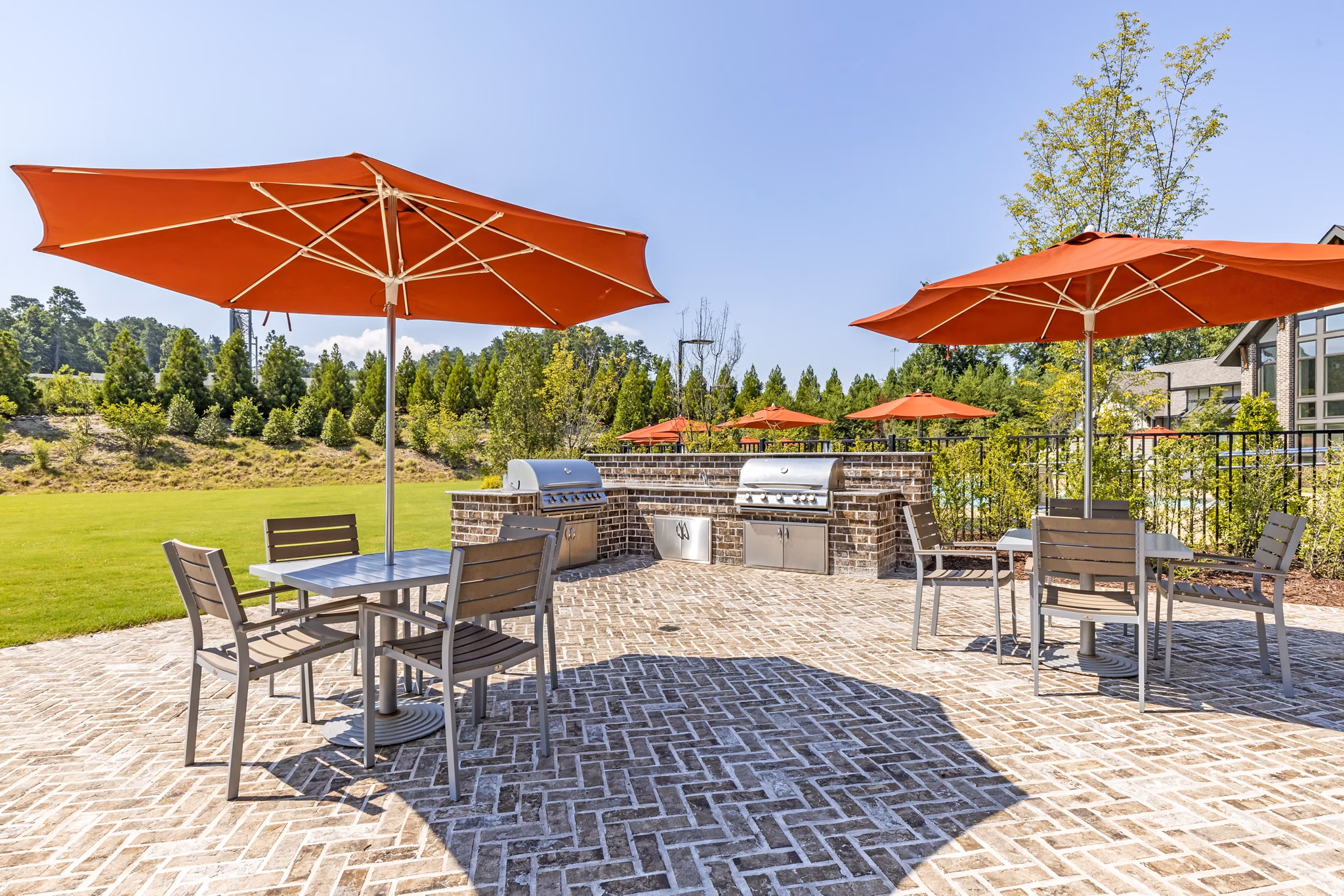 Grilling area and patio at Grand Oaks at Crane Creek Apartments featuring outdoor seating and lush surroundings