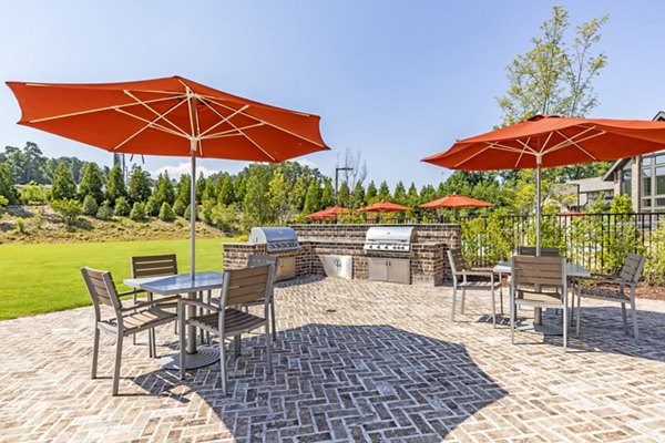 Grilling area and patio at Grand Oaks at Crane Creek Apartments featuring outdoor seating and lush surroundings
