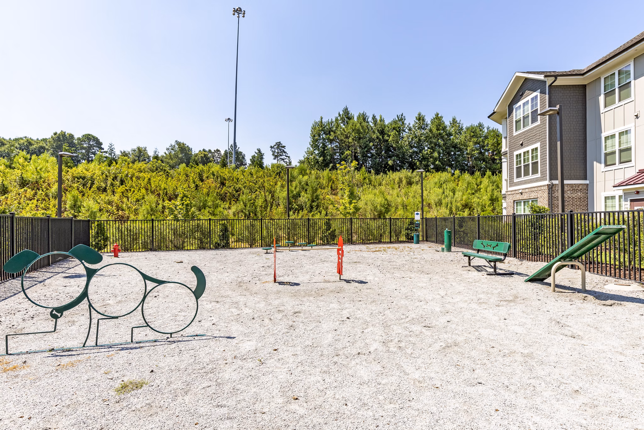 Spacious dog park at Grand Oaks at Crane Creek Apartments with agility equipment and green open space