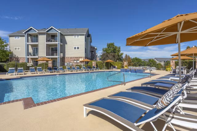 Luxury outdoor swimming pool area with lounge chairs and umbrellas at Greystar luxury apartments