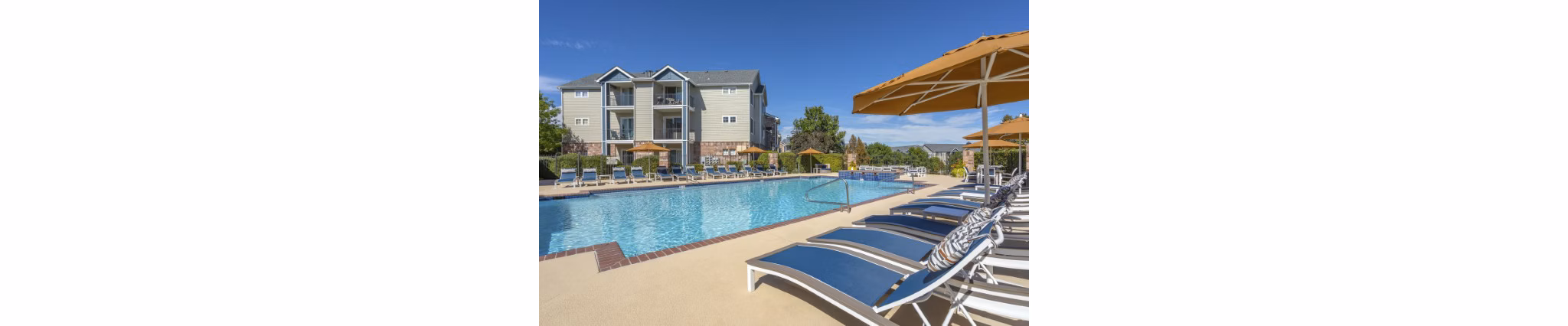 Luxury outdoor swimming pool area with lounge chairs and umbrellas at Greystar luxury apartments