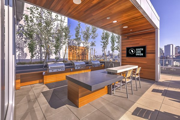 Outdoor grilling station with modern seating at Ascent South Lake Union Apartments, ideal for social gatherings and BBQs