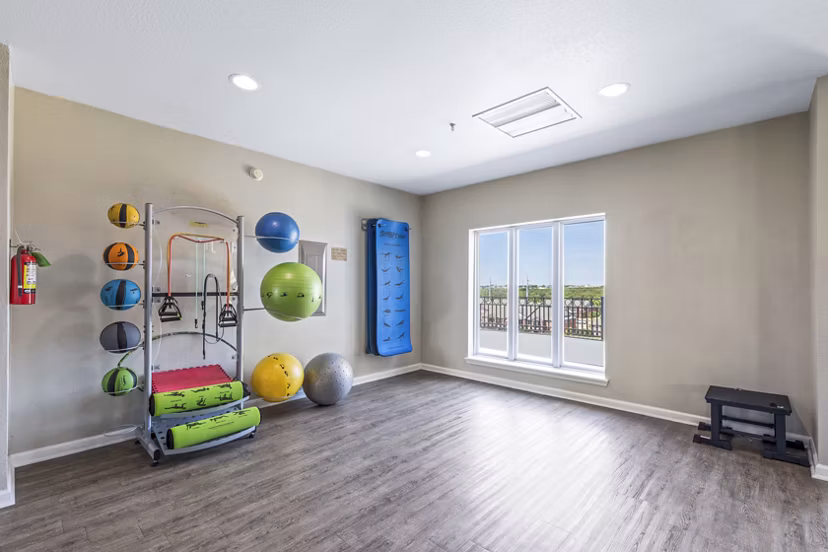 Yoga studio with hardwood floors and mirrors at Timberlinks at Denton Apartments offering fitness amenities and community wellness spaces