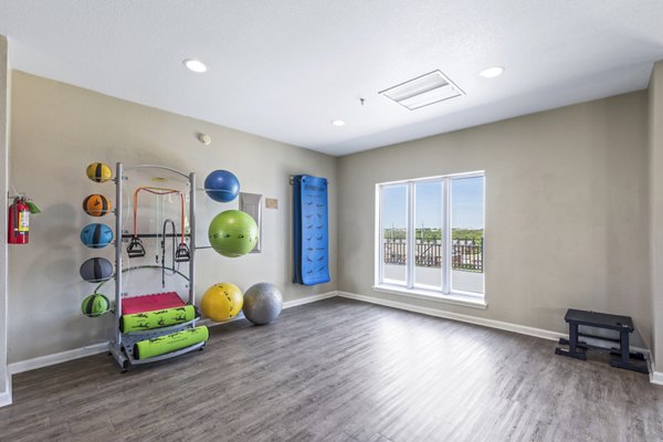 Yoga studio with hardwood floors and mirrors at Timberlinks at Denton Apartments offering fitness amenities and community wellness spaces