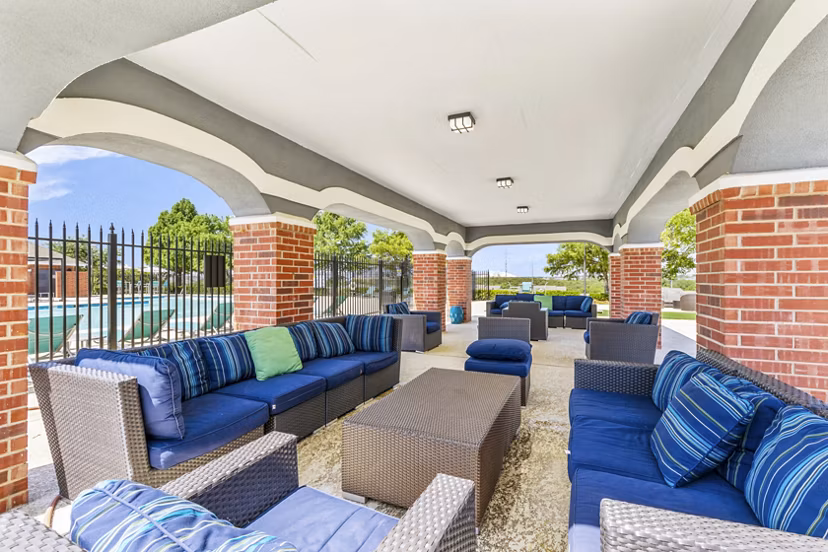 Modern outdoor patio space with seating and BBQ grill at Timberlinks at Denton Apartments