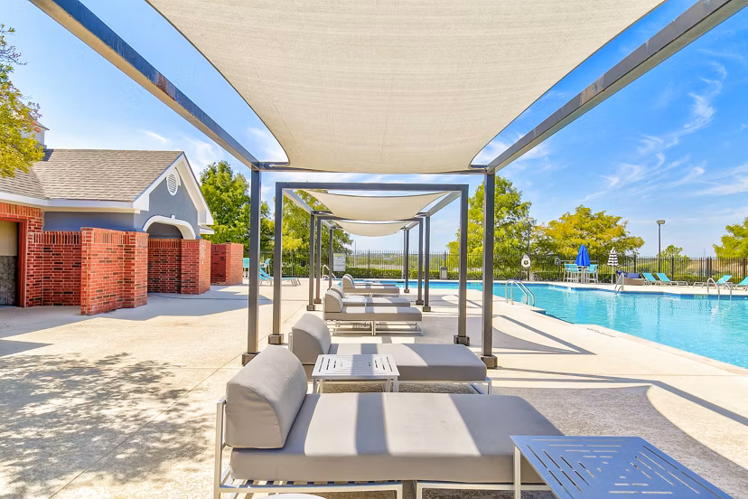 Inviting poolside patio with loungers and umbrellas at Timberlinks at Denton Apartments, perfect for relaxation and socializing