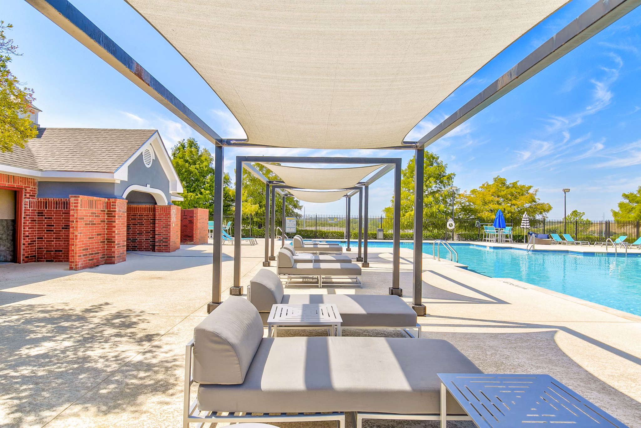 Inviting poolside patio with loungers and umbrellas at Timberlinks at Denton Apartments, perfect for relaxation and socializing