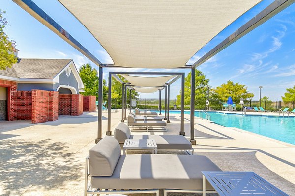 Inviting poolside patio with loungers and umbrellas at Timberlinks at Denton Apartments, perfect for relaxation and socializing