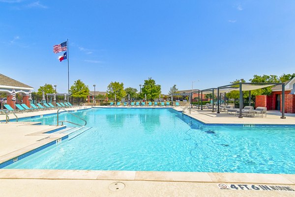 Poolside relaxation area at Timberlinks at Denton Apartments featuring sun loungers and lush landscaping, ideal for outdoor enjoyment and leisure