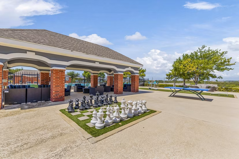 Outdoor patio with lush greenery at Timberlinks at Denton Apartments' recreational area