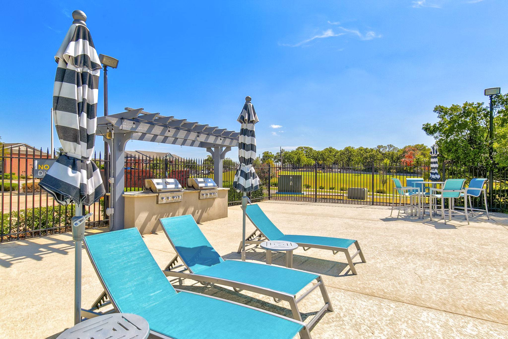 Outdoor grill area with modern patio furniture at Timberlinks at Denton Apartments, perfect for hosting gatherings and enjoying outdoor living