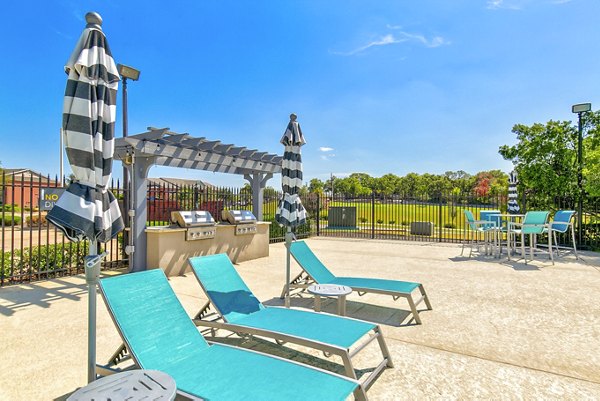 Outdoor grill area with modern patio furniture at Timberlinks at Denton Apartments, perfect for hosting gatherings and enjoying outdoor living