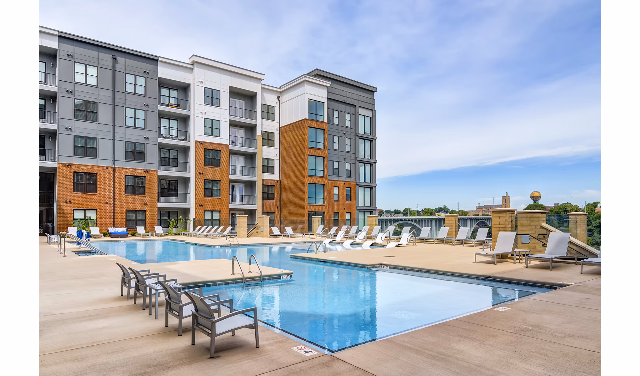 Relaxing poolside retreat at One Riverwalk Apartments featuring luxurious sun loungers and lush landscaping, enhancing outdoor leisure experience