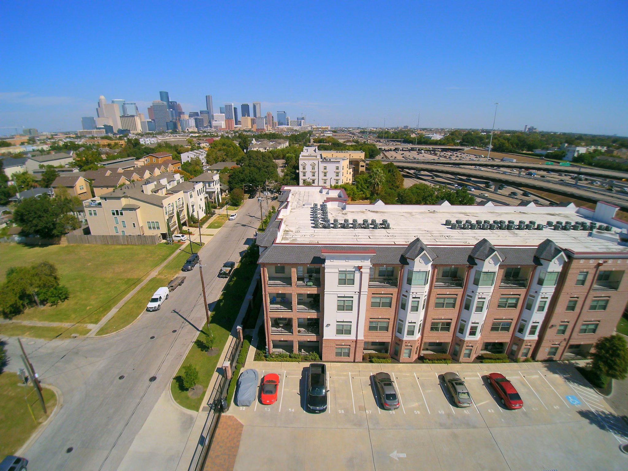 Aerial view showcasing luxury apartments and parking in a vibrant residential area with a city skyline