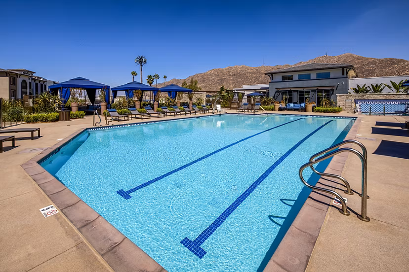 Outdoor pool area with lounge seating at Core at Sycamore Highlands, luxury apartments by Greystar in a serene setting