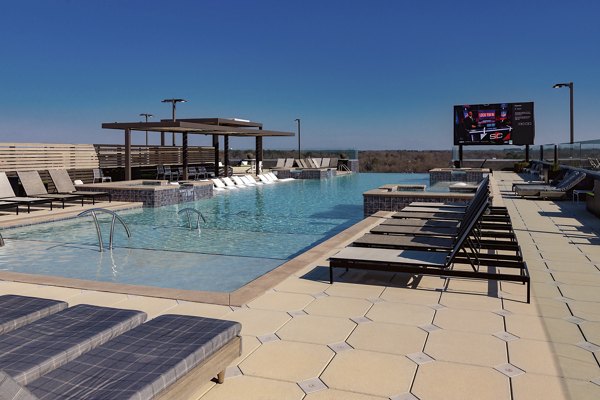 Olympic-sized pool at The Standard at Athens Apartments with lounge seating and landscaped surroundings