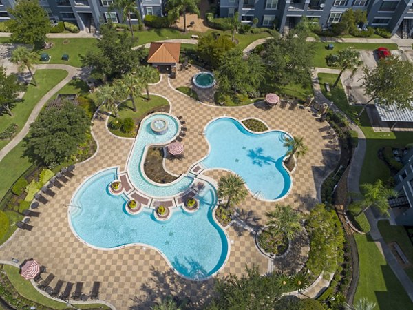 Oversized resort-style pool at Mandalay at Shadow Lake Apartments with lush landscaping and lounge seating