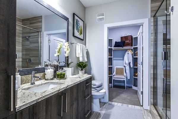 Bathroom with luxurious marble tiles and glass-enclosed shower at Overture Dr Phillips Apartments