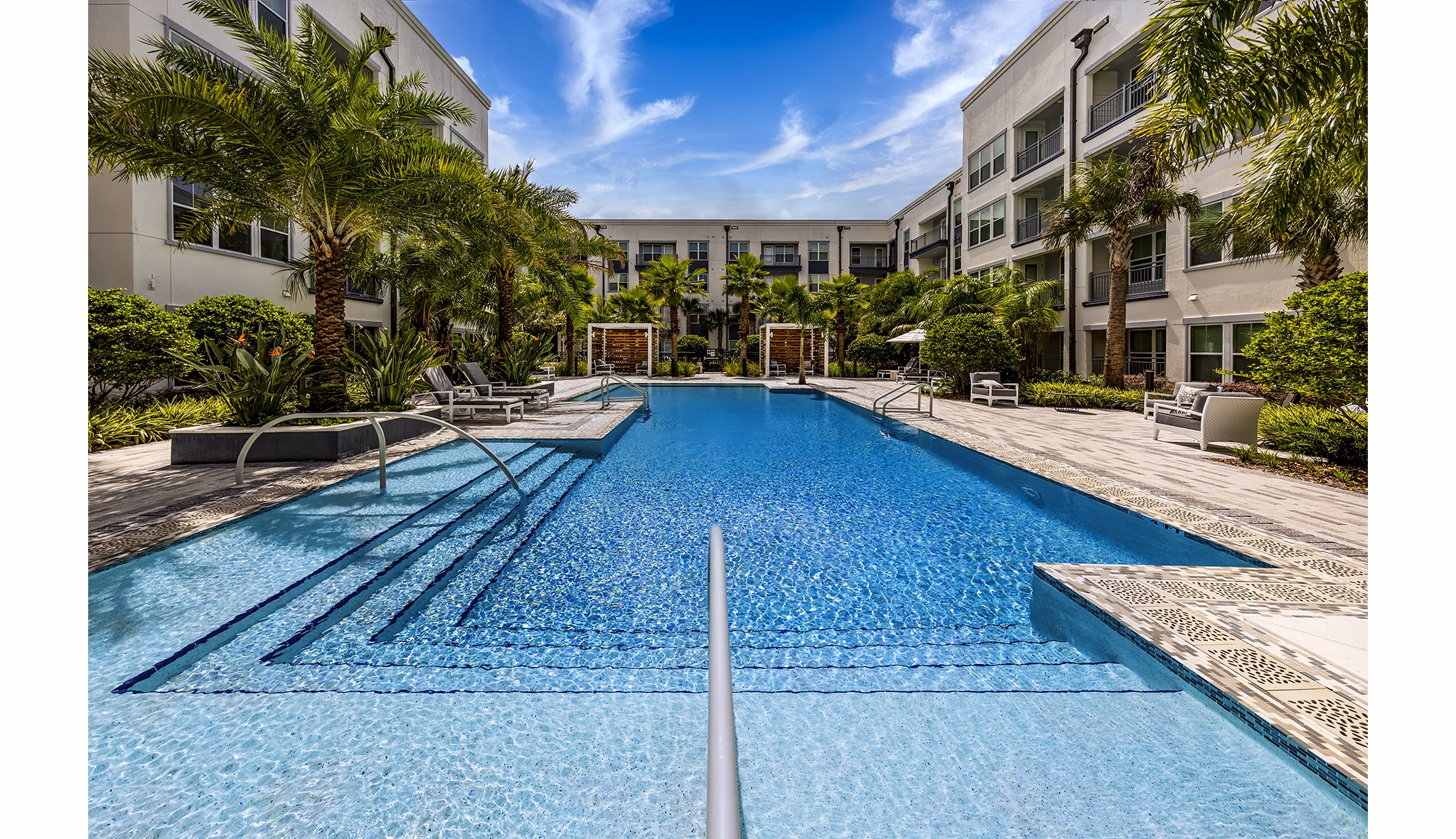 Modern pool surrounded by lush greenery at Overture Dr Phillips Apartments