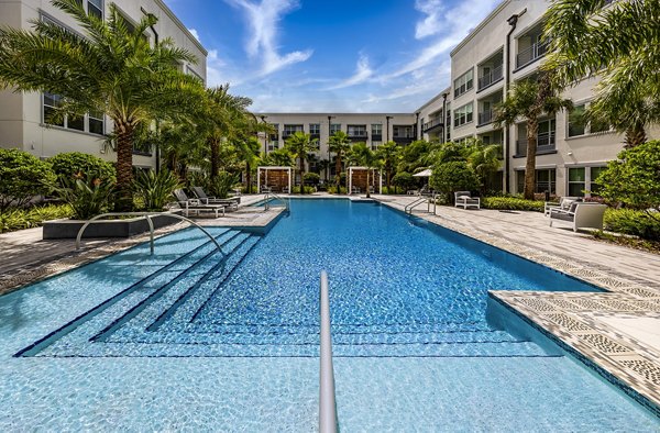 Modern pool surrounded by lush greenery at Overture Dr Phillips Apartments