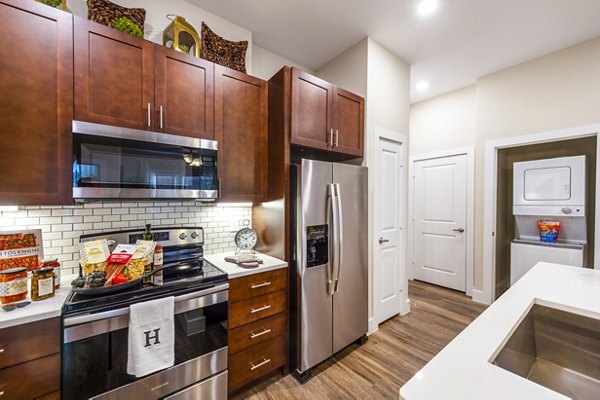 Modern kitchen with granite countertops and stainless steel appliances in Hardy Yards Apartment Homes
