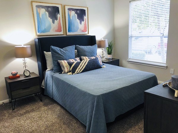 Cozy bedroom with modern decor and large windows at Breakers at Windmill Lakes Apartments