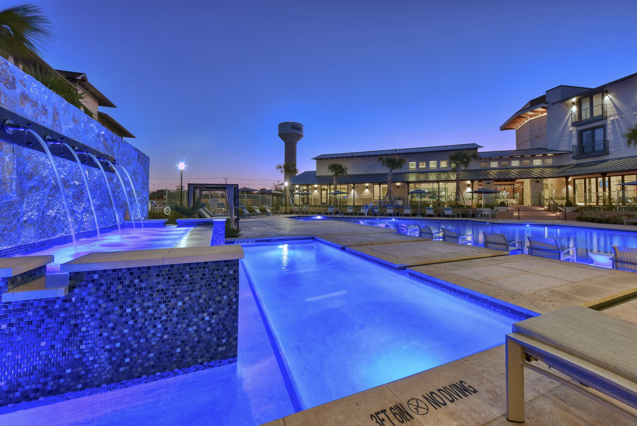 Resort-style pool with sun loungers at Tacara Westpointe Village Apartments, offering luxury amenities for relaxation and recreation