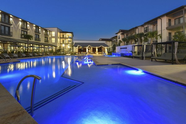 Resort-style pool at Tacara Westpointe Village Apartments with lounge seating and lush landscaping