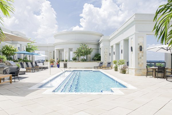 Luxurious poolside oasis at The Residence at SouthPark Apartments, featuring relaxing sun loungers and lush landscaping