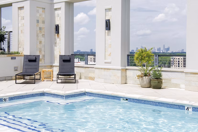 Outdoor pool with sun loungers and umbrellas at The Residence at SouthPark Apartments